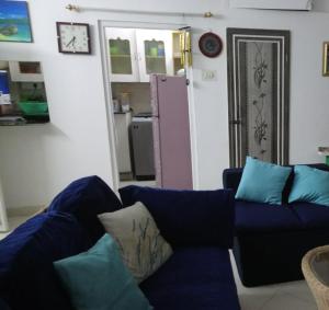 a living room with a blue couch and a kitchen at Casa di Mara in Puttaparthi
