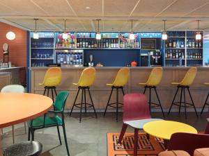 un restaurante con sillas coloridas y un bar en B&B HOTEL Paris 17 Batignolles, en París