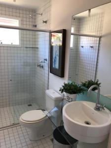 a white bathroom with a toilet and a sink at Casa em Arraial d’Ajuda in Porto Seguro