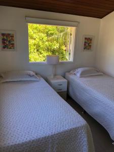 two beds in a bedroom with a window at Casa em Arraial d’Ajuda in Porto Seguro