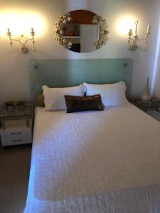 um quarto com uma grande cama branca e um espelho em Casa em Arraial d’Ajuda em Porto Seguro