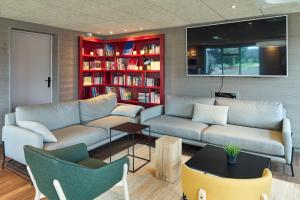 a living room with two couches and a book shelf at Campanile Villennes-Sur-Seine - Poissy - Hôtel rénové en 2024 in Villennes-sur-Seine