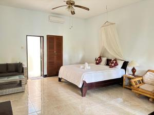 Bahari Beach Amed في آميد: غرفة نوم بيضاء مع سرير وأريكة