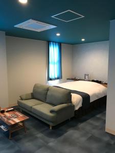 ein Schlafzimmer mit einem Bett, einem Sofa und einem Fenster in der Unterkunft Ocean Hotel adult only - former Kagoshima Intelligence in Kagoshima