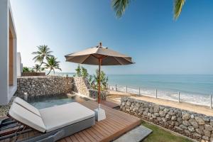 a patio with an umbrella and a chair and a pool at Casa De La Flora - SHA Extra Plus in Khao Lak