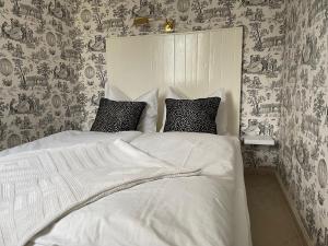 una camera da letto con un letto con lenzuola bianche e carta da parati di Strandgut a Rostock