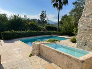a swimming pool in a garden with a stone wall at Magnificent Renovated Bergerie 6 Bedroom 6 Bathroom in Saint Paul de Vence