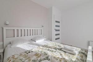 a white bedroom with a bed with white sheets and pillows at LTC Apartments Ujejskiego in Gdynia
