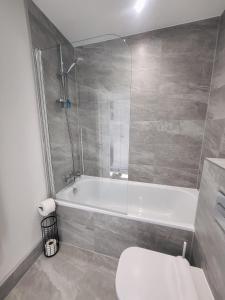 y baño con bañera, aseo y ducha. en Private room in townhouse near Heathrow & Windsor en Burnham