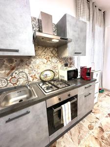 uma cozinha com um lavatório e um fogão forno superior em Il Rifugio Storico in Piazza em Augusta