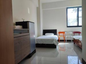 1 dormitorio con 2 camas, vestidor y 2 sillas en Dahu Yipinyuan B&B, en Ta-hu