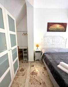 um quarto com uma cama branca e uma porta de vidro em Il Rifugio Storico in Piazza em Augusta
