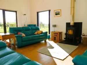 a living room with a blue couch and a fireplace at The Longhouse in Castle Douglas