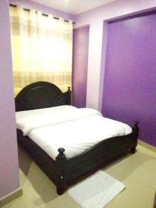 a bedroom with a bed with a purple wall at Suzie Kampala Uganda in Kampala