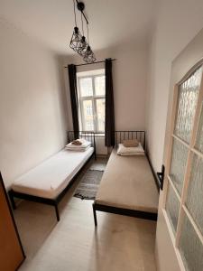 two beds in a room with a window at Apartament 2 pokoje, Przemyśl, 1 piętro in Przemyśl