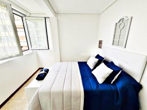 a bedroom with a large bed with blue sheets and pillows at Holibai, Apt Mencer, Playa América Al Lado Del Mar in Nigrán