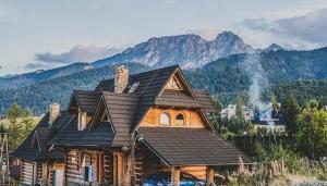 ein großes Holzhaus mit Bergen im Hintergrund in der Unterkunft Domek VIP PIETIA in Zakopane