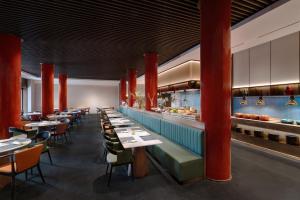 a restaurant with long tables and red columns at SSAW Garden Hotel Beijing in Beijing