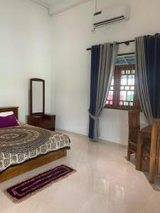 a bedroom with a bed and a table and a window at Norwegian House in Bentota