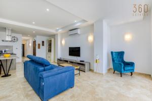 un soggiorno con divano blu e TV di Top of the world 2BR home with spectacular views by 360 Estates a Mellieħa