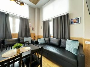 Una sala de estar con un sofá de cuero negro y una mesa. en Lliri 32, en Valencia