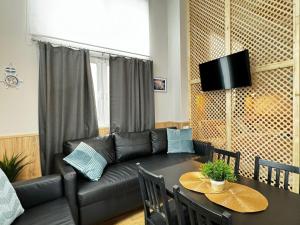 a living room with a black leather couch and a table at Grandera Apart`s - Lliri 32 in Valencia