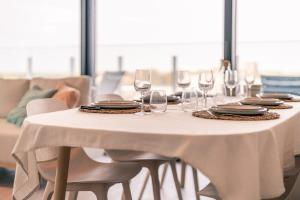 a white table with wine glasses and plates on it at Huswell - Modern new apartment with pool access and parking in Ostend