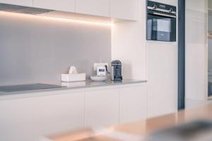 a kitchen with white walls and a counter with a coffee maker at Huswell - Modern new apartment with pool access and parking in Ostend