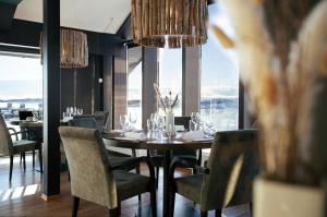 a dining room with a table and chairs and windows at Panorama Hotell & Resort in Steinsland