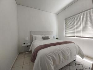 a white bedroom with a large bed and a window at 931 Ballito Groves in Ballito
