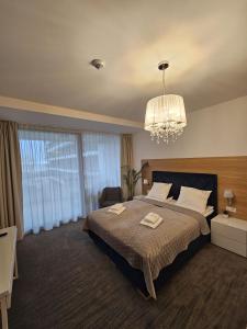 a bedroom with a large bed and a chandelier at NCM Apartments Seaside Park in Kołobrzeg