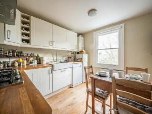 cocina con armarios blancos y mesa de madera en Pass the Keys Stylish London Flat near Station - Victoria 20 min, en Londres