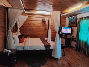 a bedroom with a canopy bed with a television in it at Maekhong Delta Boutique Hotel in Mae Sai