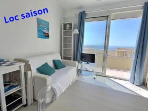 a living room with a white couch and a large window at Appartement vue mer en plein centre de Valras-Plage in Valras-Plage