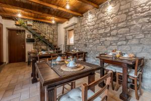 ein Restaurant mit Holztischen und -stühlen und einer Steinmauer in der Unterkunft IL RICHIASTRO MEDIEVALE in Viterbo