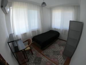 a small bedroom with a black bed and a chair at Gazipasa/Alanya Airport Apt 5minBEACH/5minAIRPORT in Gazipasa