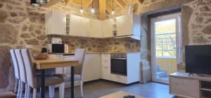 a kitchen with white cabinets and a table with chairs at Casa do Rio - AL in Valença