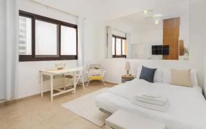 Manzil - Studio Apartment in Dubai Silicon Oasis near Dubai Outlet Mall في دبي: غرفة نوم بيضاء مع سرير أبيض وطاولة