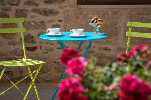a blue table with two chairs and two cups and a glass at Arismari Houses - Levanda & Rosa in Pómbia