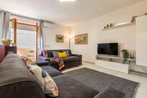 un soggiorno con divano e TV di White lilium apartment - Magnolia holidays ad Alghero