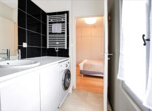 La salle de bains est pourvue d'un lavabo et d'un lave-linge. dans l'établissement Appartement T2 de Luxe face au Jardin Public, à Bordeaux