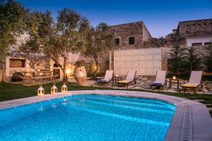 a swimming pool in a yard with chairs and a house at Arismari Houses - Levanda & Rosa in Pómbia