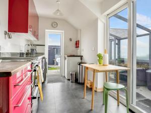 a kitchen with red cabinets and a table and a window at Pass the Keys Beautiful Sea View House in Borth