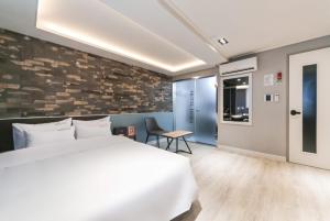 a bedroom with a white bed and a stone wall at Hotel Hora in Tongyeong