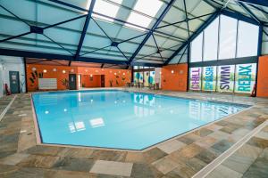 a large swimming pool in a building with windows at Idyllic Lakeview Lodge in Chichester
