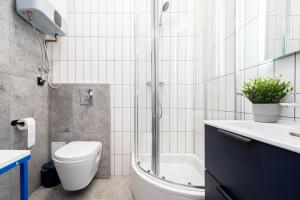 a bathroom with a toilet and a sink and a shower at Apartament Indygo16 in Kalisz
