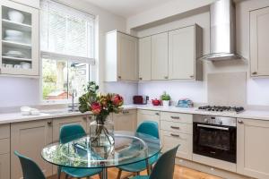 ロンドンにあるMadison Hill - Byrne Garden 1 - Two bedroom homeのキッチン(ガラステーブル、青い椅子付)