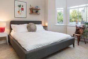 ロンドンにあるMadison Hill - Byrne Garden 1 - Two bedroom homeの大きなベッド1台(窓2つ付)が備わるベッドルームです。