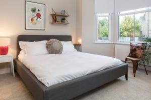 a large bed in a bedroom with two windows at Madison Hill - Byrne Garden 1 - Two bedroom home in London