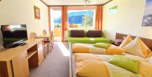 ein Hotelzimmer mit 2 Betten und einem TV in der Unterkunft Haus Löger Apartments Pyhrn Priel in Windischgarsten